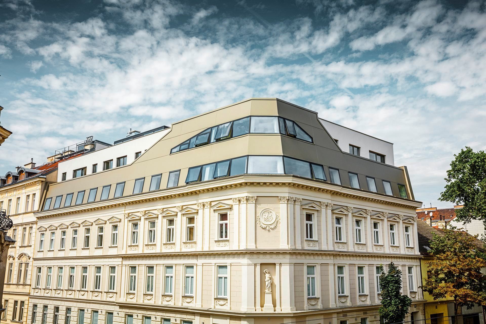 Ein Foto von einem Altbau mit einer modernen Metallfassade im Dachgeschoss